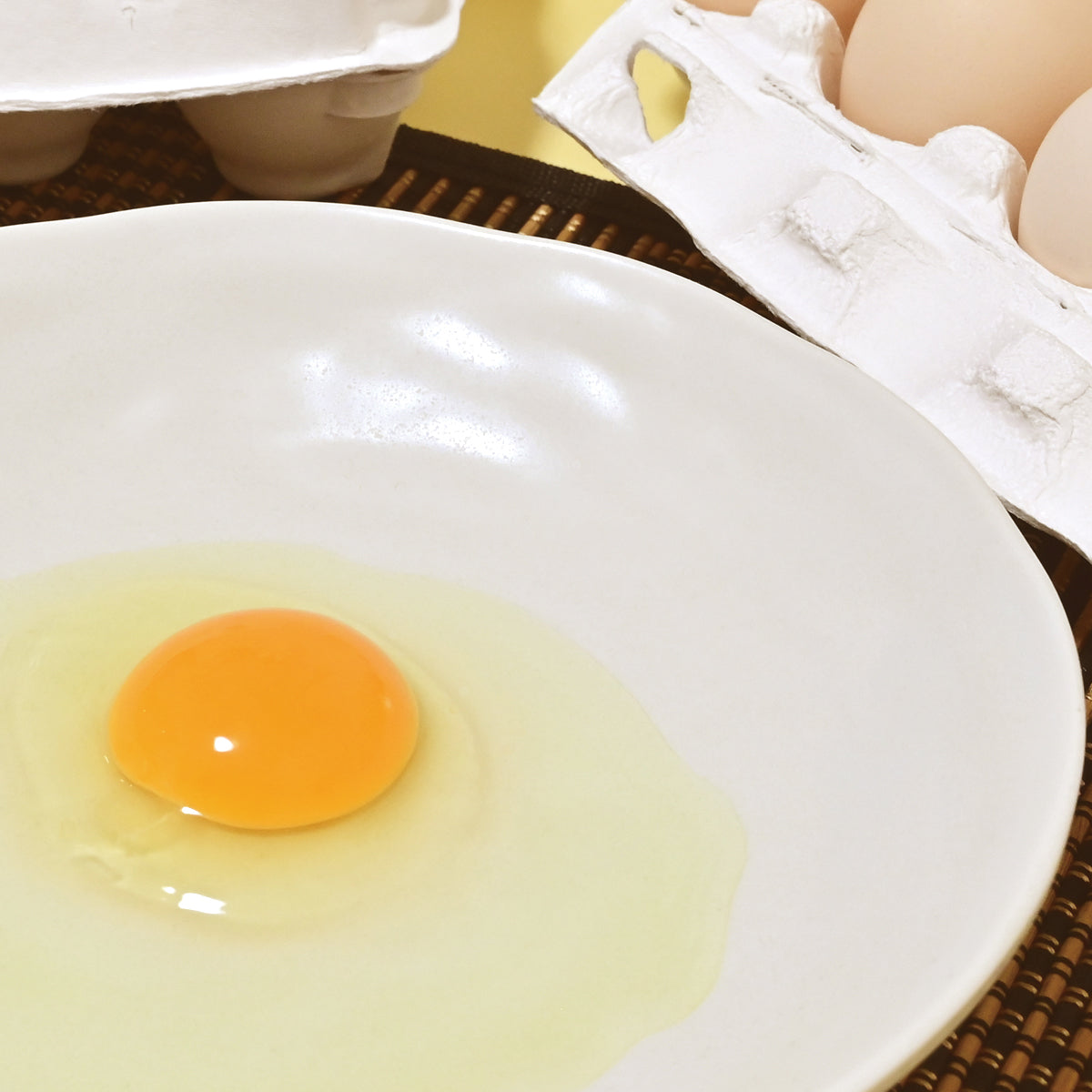 白い皿の上の生卵の黄身と白身